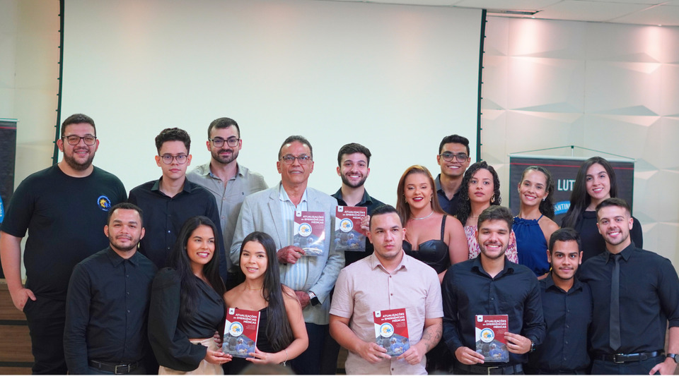 Foto colorida com os organizadores e autores do livro segurando a obra que possui um detalhe vermelho. 